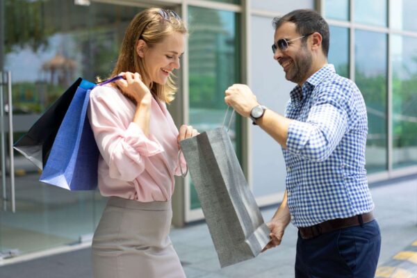 sonriente-mediados-hombre-adulto-que-muestra-su-compra-mujer-joven
